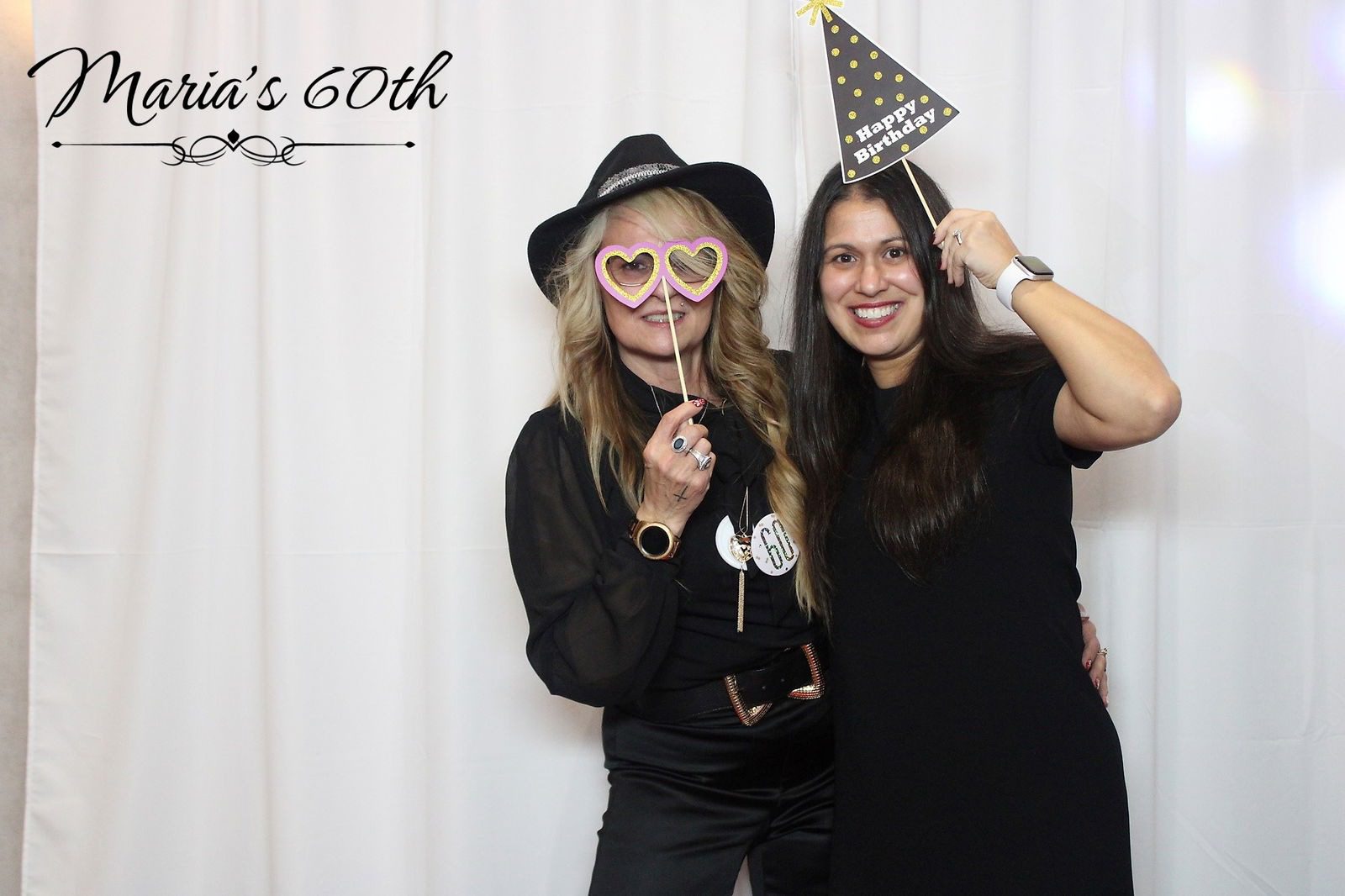 Two women celebrating a 60th birthday with fun party props.
