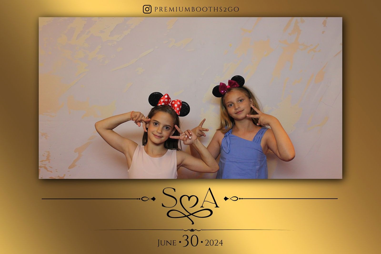 Two young girls wearing Minnie Mouse ears pose playfully in front of a decorative backdrop.