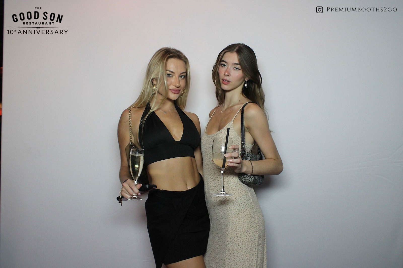 Two stylish women holding champagne glasses in elegant outfits.