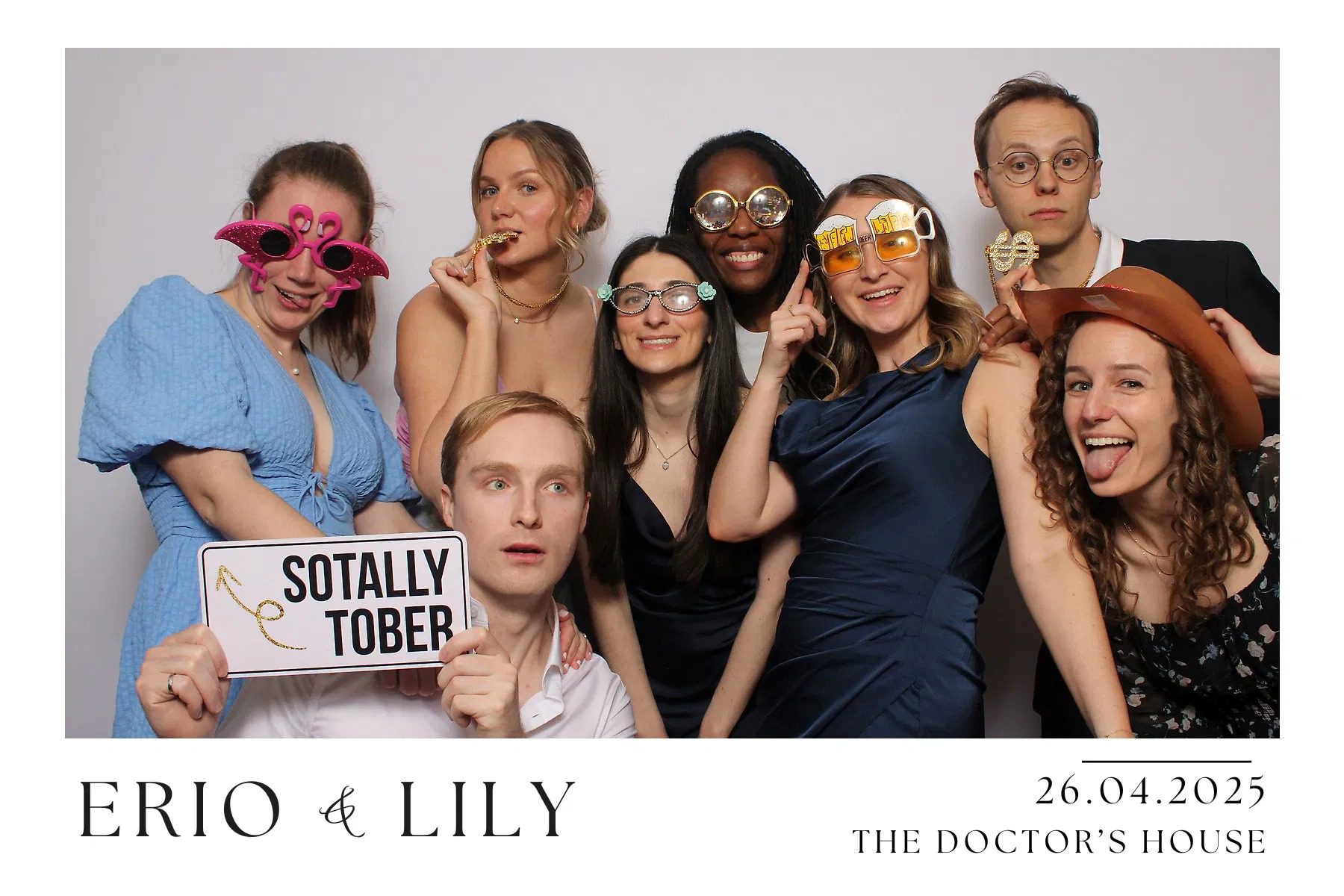 A group of friends posing with funny glasses at a photo booth event.