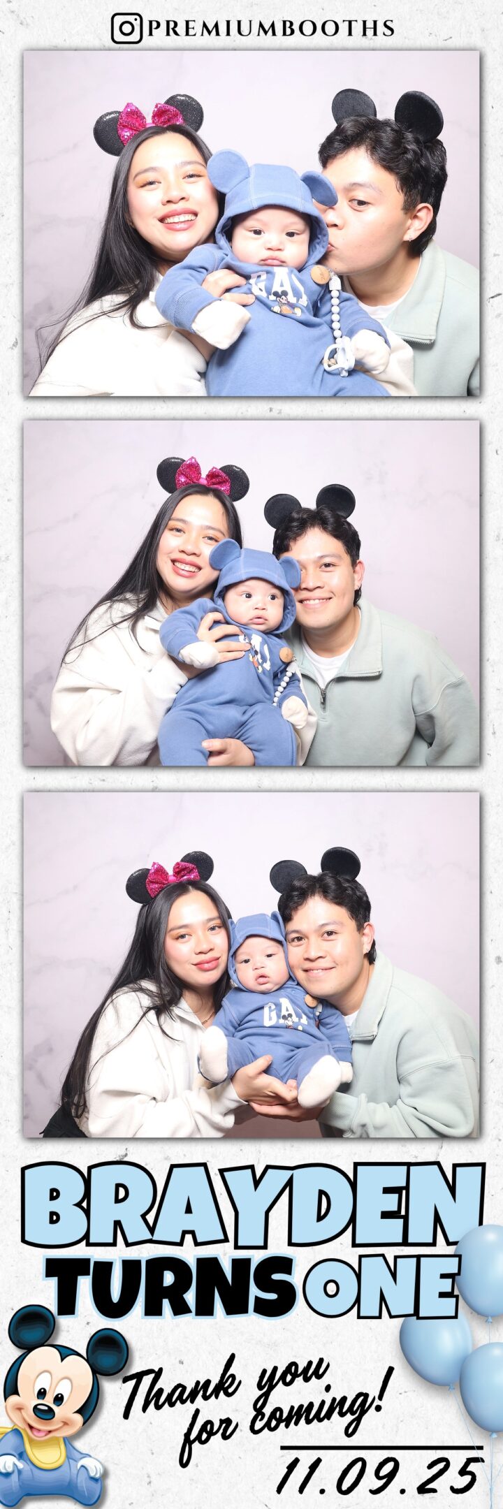 A happy family with a baby wearing blue and parents in mouse ear headbands.