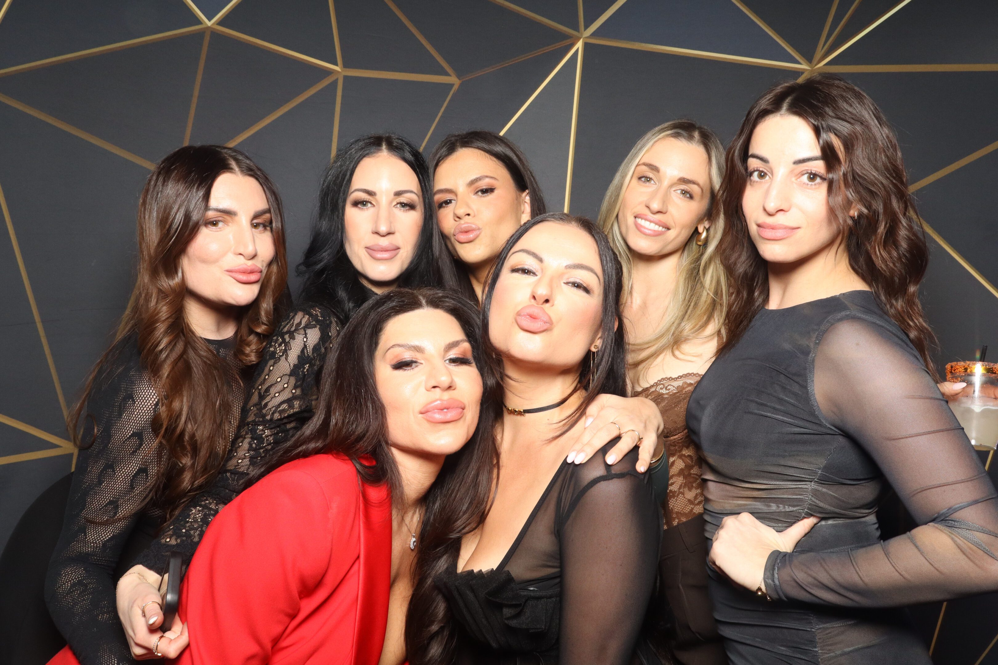 Group of seven women posing together at a party.