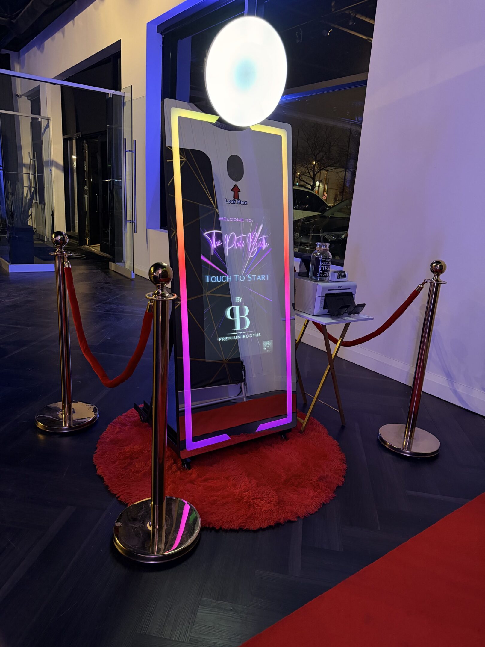 Interactive photo booth with touch screen and red carpet setup.