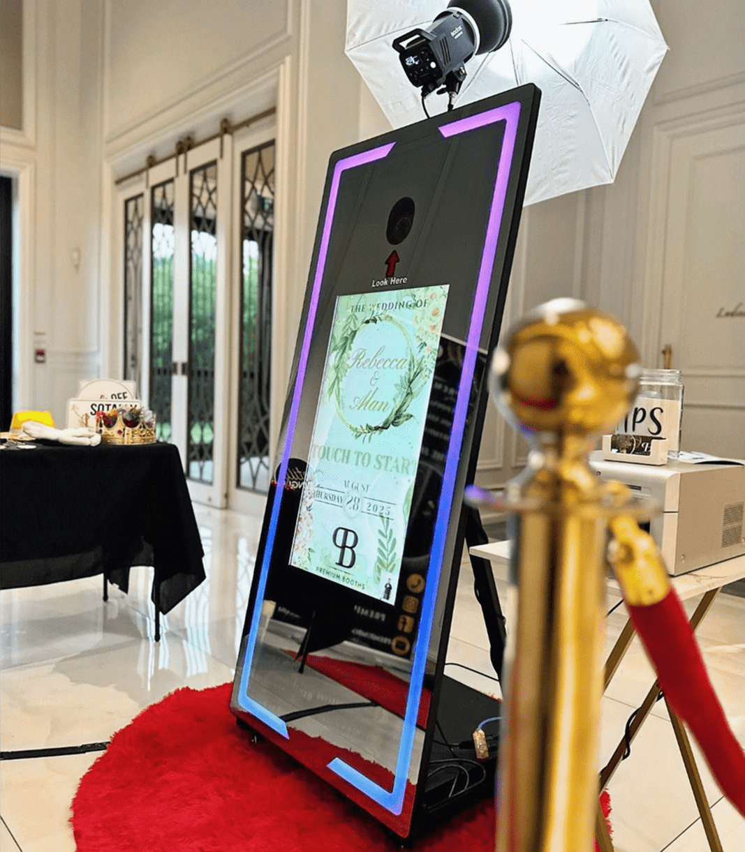Interactive digital mirror display at an event with a red carpet and rope barrier.