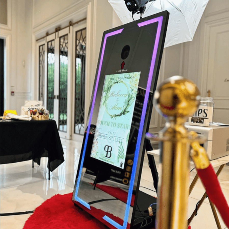A sleek photo booth with a red carpet and golden stanchions.